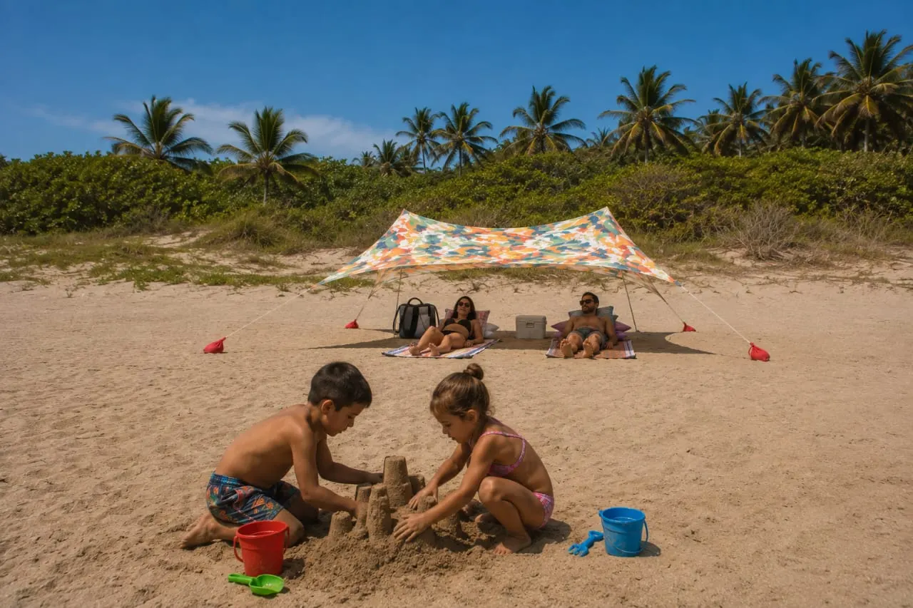 Dos niños construyendo un castillo de arena frente a una carpa Shadow.